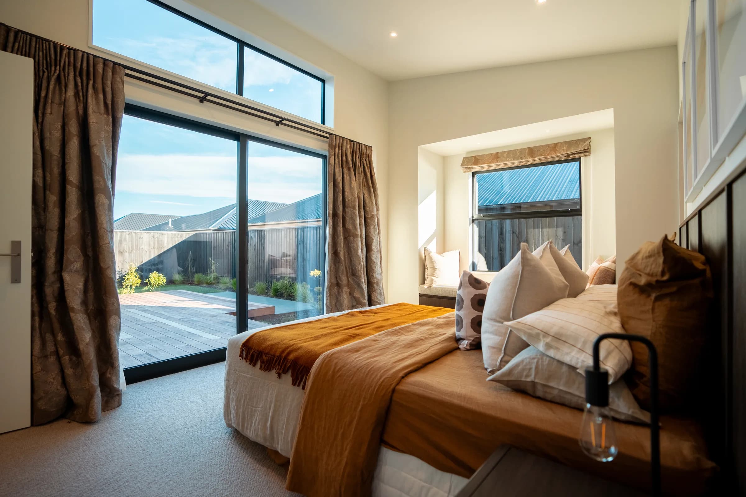 A bedroom in a Pringle home, its sliding door open to a private courtyard and deck